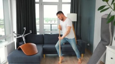 Adam evi temizliyor ve süpürgeyle dans ediyor. Yavaş çekim