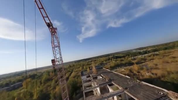 Беспилотник FPV плавно летает среди заброшенных промышленных зданий и вокруг экскаватора. — стоковое видео