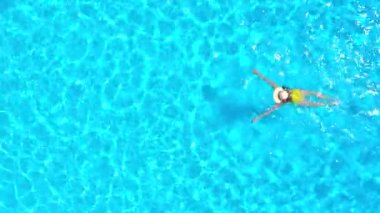 Sarı mayo giymiş bir kadının havuzda yüzüşünü yukarıdan izleyin. Yaz yaşam tarzı