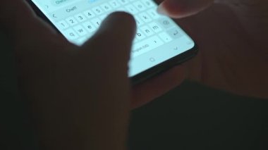 Akıllı telefondan yazı yazan bir kadın eli. Yakın plan. Akşamları akıllı telefonları kullanarak.