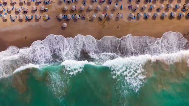 Вид с воздуха на море, песчаный пляж, солнечные зонтики и шезлонги, неузнаваемые люди. Отдых и туризм на Крите, Греция. — стоковое видео