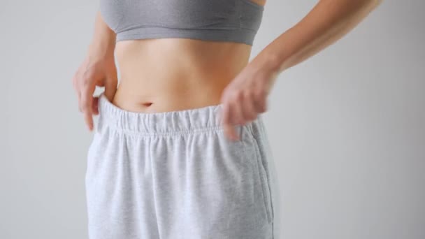 Woman puts on her pants and strokes her stomach. Concept of healthy digestion. — Stock Video