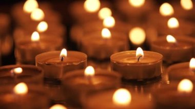 Siyah arkaplanda yanan çok sayıda küçük mum