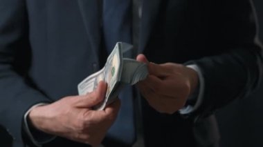 Resmi olarak giyinmiş adam Amerikan dolarlarını sayıyor. Yatırım, başarı, finansal beklentiler veya kariyer ilerlemesi kavramı