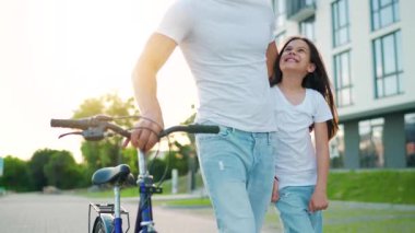 Baba ve kızı gün batımında bisiklet sürdükten sonra kendi alanlarında dolaşıyorlar. Yavaş çekim