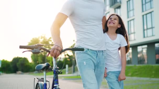 Papà e figlia camminano nella loro zona dopo aver pedalato al tramonto. Rallentatore — Video Stock