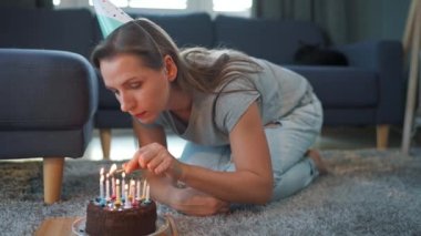 Doğum günü pastasında mum yakan bir kadın, evde yalnız başına doğum gününü kutluyor.