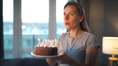 Mutlu, heyecanlı bir kadın Noel pastasına mum üflüyor, doğum gününü evde kutluyor, ağır çekimde.