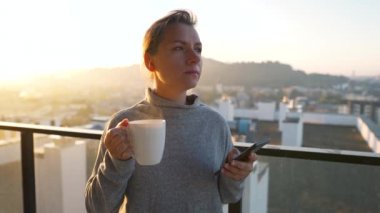 Kadın güne bir fincan çay ya da kahveyle başlıyor ve şafak vakti balkondaki akıllı telefonundaki e-postaları kontrol ediyor..
