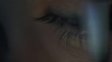 Woman in glasses looking on the monitor and surfing Internet. The monitor screen is reflected in the glasses. Work at night. Remote work