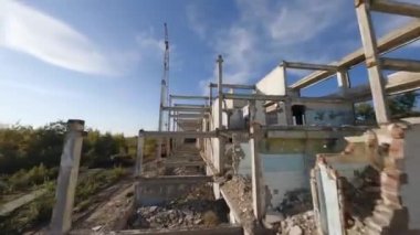 FPV insansız hava aracı terk edilmiş sanayi binaları ve bir kazıcının etrafında sorunsuzca uçuyor..