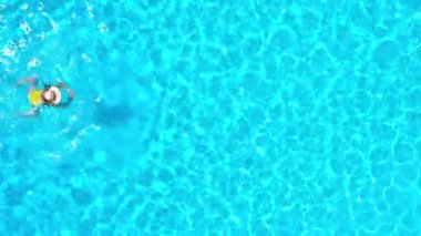 Sarı mayo giymiş bir kadının havuzda yüzüşünü yukarıdan izleyin. Yaz yaşam tarzı