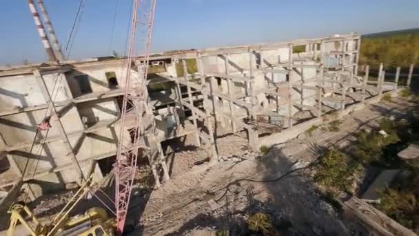 FPV insansız hava aracı terk edilmiş sanayi binaları ve bir kazıcının etrafında sorunsuzca uçuyor.. — Stok video