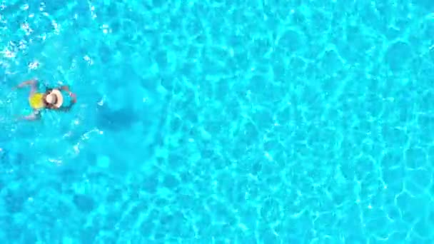 Utsikt från toppen som en kvinna i gul baddräkt simmar i poolen. Sommar livsstil — Stockvideo