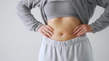 Karın ve yanlarına baskı yapan kadın deri altında fazla yağ var mı diye kontrol ediyor.