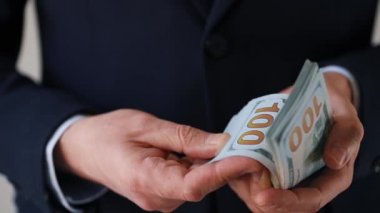 Resmi olarak giyinmiş adam Amerikan dolarlarını sayıyor. Yatırım, başarı, finansal beklentiler veya kariyer ilerlemesi kavramı