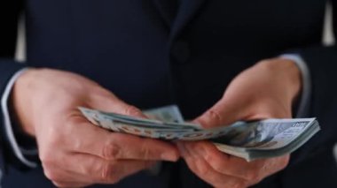 Resmi olarak giyinmiş adam Amerikan dolarlarını sayıyor. Yatırım, başarı, finansal beklentiler veya kariyer ilerlemesi kavramı