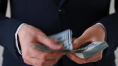 Resmi olarak giyinmiş adam Amerikan dolarlarını sayıyor. Yatırım, başarı, finansal beklentiler veya kariyer gelişimi kavramı. Hızlandırılmış video