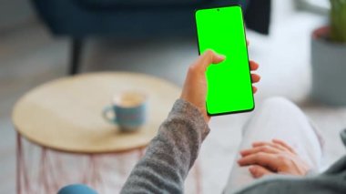 Evde dikey modda yeşil ekranlı akıllı telefon kullanan bir kadın var. Kız internette geziniyor, içeriği izliyor, videolar izliyor. POV.