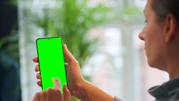 Mujer en casa usando smartphone con pantalla verde en modo vertical. Chica navegando por Internet, viendo contenido, videos — Vídeos de Stock