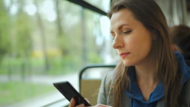 Woman in tram using smartphone chatting and texting with friends. City, urban, transportation. — Vídeo de stock