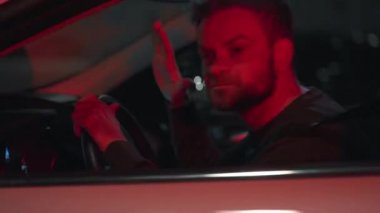 Man sits in a car, angry and upset that he was stopped by the police for a traffic violation