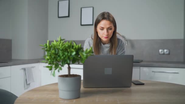 Woman standing in home cozy kitchen and use laptop do freelance work, chatting with someone, answering e-mail. Concept of remote work. — Wideo stockowe