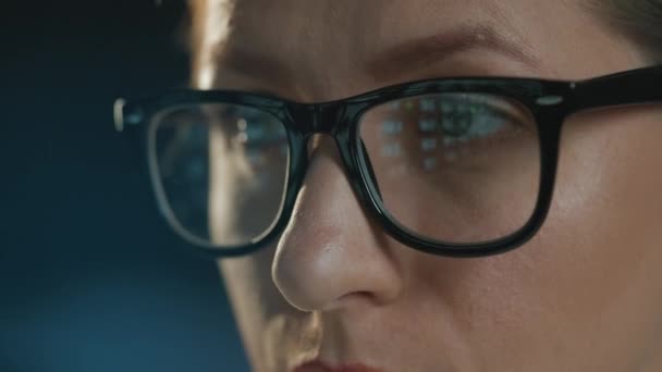 Žena v brýlích, dívá se na monitor a pracuje s daty a analytikou. Obrazovka monitoru se odráží v brýlích. Práce v noci. Extrémní detail — Stock video