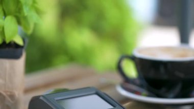 NFC kredi kartı ödemesi. NFC teknolojisiyle bağlantısız kredi kartıyla ödeme yapan bir kadın bir kafedeki banka terminalinden sipariş veriyor. Kablosuz para transferi. Kablosuz ödeme