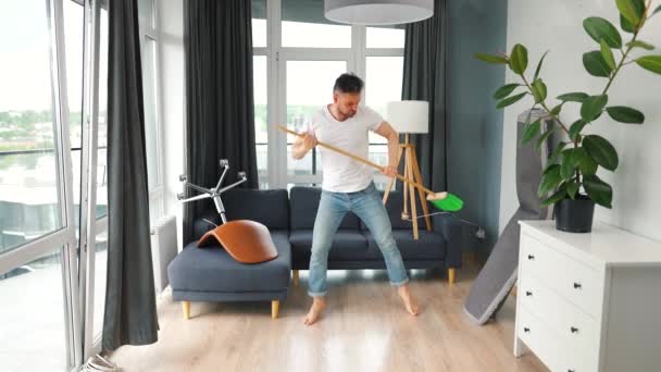 Een man die het huis schoonmaakt en plezier heeft met dansen met een bezem. Langzame beweging — Stockvideo