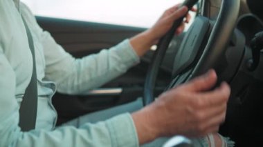 Adam yakın çekimde araba kullanıyor.