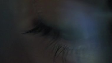 Woman in glasses looking on the monitor and surfing Internet. The monitor screen is reflected in the glasses. Work at night. Remote work