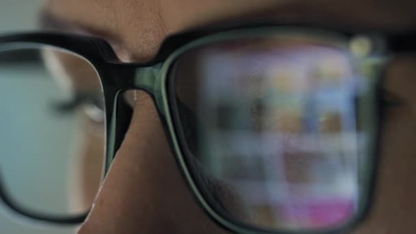 Γυναίκα με γυαλιά που κοιτάει στην οθόνη και σερφάρει στο ίντερνετ. Η οθόνη της οθόνης αντανακλάται στα γυαλιά. Δουλειά τη νύχτα. Απομακρυσμένη εργασία — Αρχείο Βίντεο