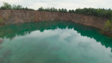 Taş ocağının merkezindeki gölün turkuaz yüzeyinden uçarak. Grodek Parkı, Polonya.