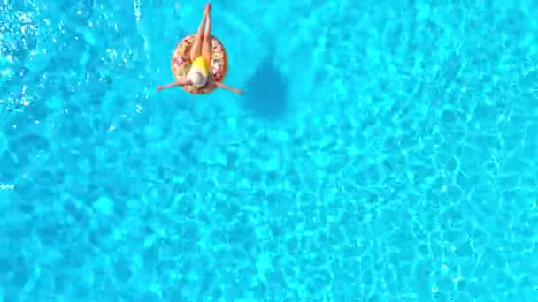 Flygfoto av en kvinna i gul baddräkt liggande på en munk i poolen — Stockvideo