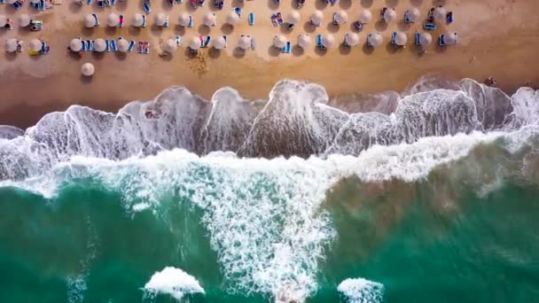 Widok z lotu ptaka na morze, piaszczysta plaża, parasole i leżaki, nierozpoznane osoby. Piękne miejsce wypoczynku i turystyki na Krecie, Grecja. — Wideo stockowe