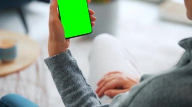 Evde dikey modda yeşil ekranlı akıllı telefon kullanan bir kadın var. Kız internette geziniyor, içeriği izliyor, videolar