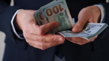 Resmi olarak giyinmiş adam Amerikan dolarlarını sayıyor. Yatırım, başarı, finansal beklentiler veya kariyer ilerlemesi kavramı