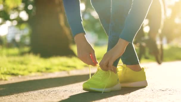 Gün batımında koşarken ya da yürürken ayakkabı bağı bağlayan bir kadın. — Stok video