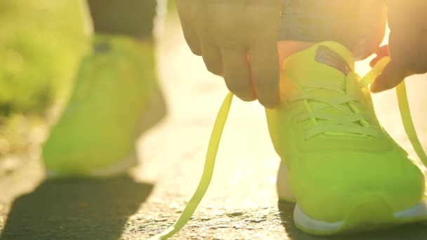 Frau bindet Schnürsenkel beim Joggen oder Gehen bei Sonnenuntergang — Stockvideo