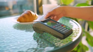 NFC kredi kartı ödemesi. NFC teknolojisiyle bağlantısız kredi kartıyla ödeme yapan bir kadın bir kafedeki banka terminalinden sipariş veriyor. Kablosuz para transferi. Kablosuz ödeme