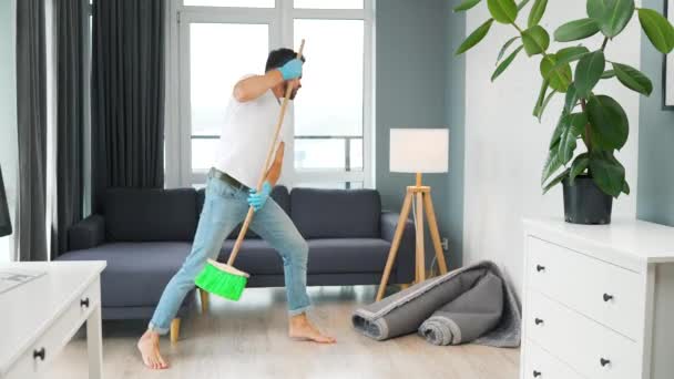 Kulaklıklı bir adam evi temizliyor ve süpürgeyle geziyor. Yavaş çekim — Stok video