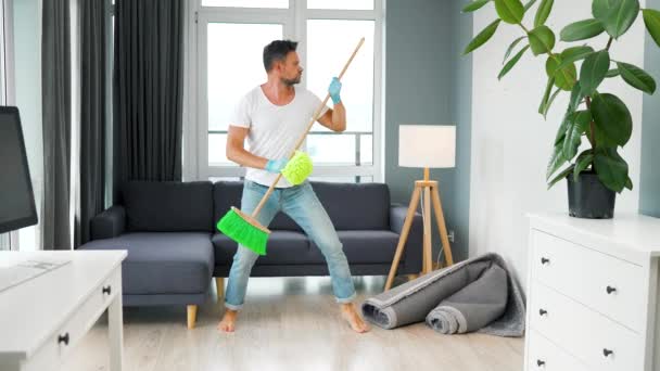 Hombre limpiando la casa y tonteando con una escoba y un paño. Movimiento lento — Vídeo de stock