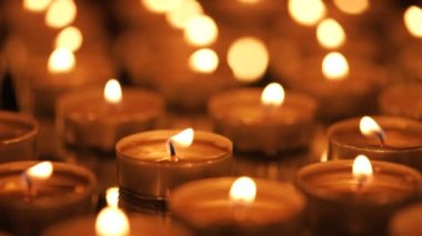 Siyah arkaplanda yanan çok sayıda küçük mum