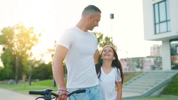 日落时，爸爸和女儿骑自行车绕着他们的区域散步。慢动作 — 图库视频影像