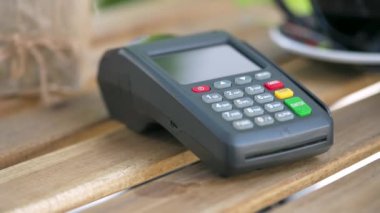 NFC kredi kartı ödemesi. NFC teknolojisiyle bağlantısız kredi kartıyla ödeme yapan bir kadın bir kafedeki banka terminalinden sipariş veriyor. Kablosuz para transferi. Kablosuz ödeme