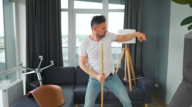 Adam evi temizliyor ve süpürgeyle dans ediyor. Yavaş çekim