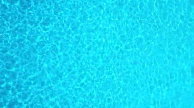 Yüzme havuzundaki saf mavi suyun yüzeyinde ışık yansımaları var. Hava görüntüleri