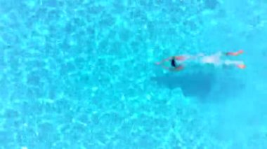 Bir adam havuza dalıp suyun altında yüzerken yukarıdan aşağıya doğru bak.