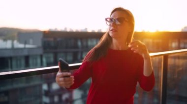 Woman taking selfie on the balcony at sunset. Slow motion